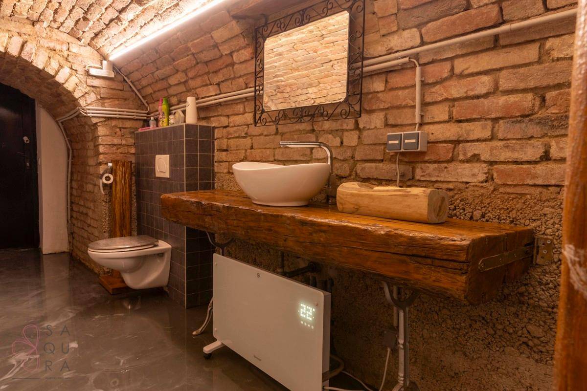 Detailansicht des Badezimmers im Gewölbekeller mit Holztischplatte, Aufsatzwaschbecken und Heizkörper.