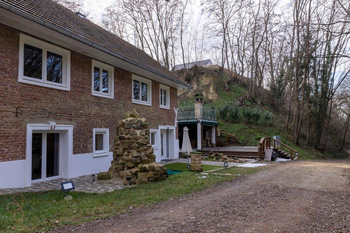 Gesamtansicht des Hauses mit Ziegelfassade, Gartenbereich und der Außenküche am Hang.