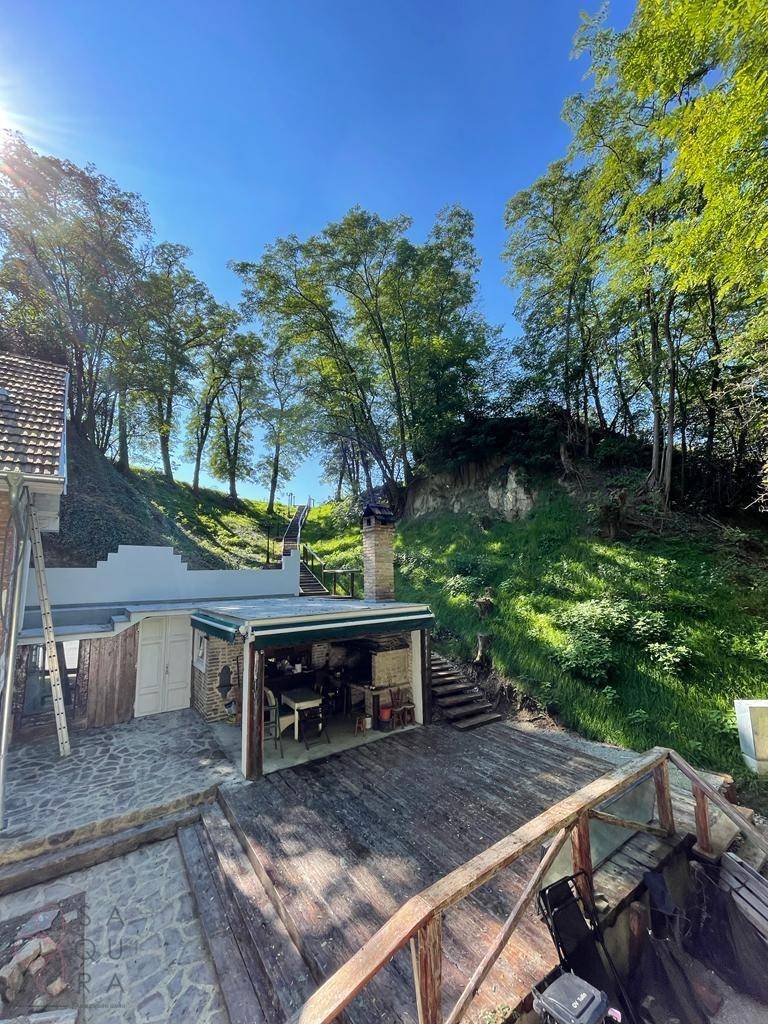 Luftaufnahme des Anwesens an einem sonnigen Tag mit Haus, Außenküche und bewaldeter Umgebung.