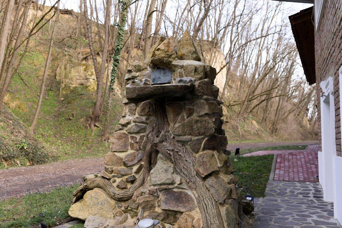 Dekorative Steinskulptur im Gartenbereich mit natürlicher Umgebung und bewaldetem Hintergrund.