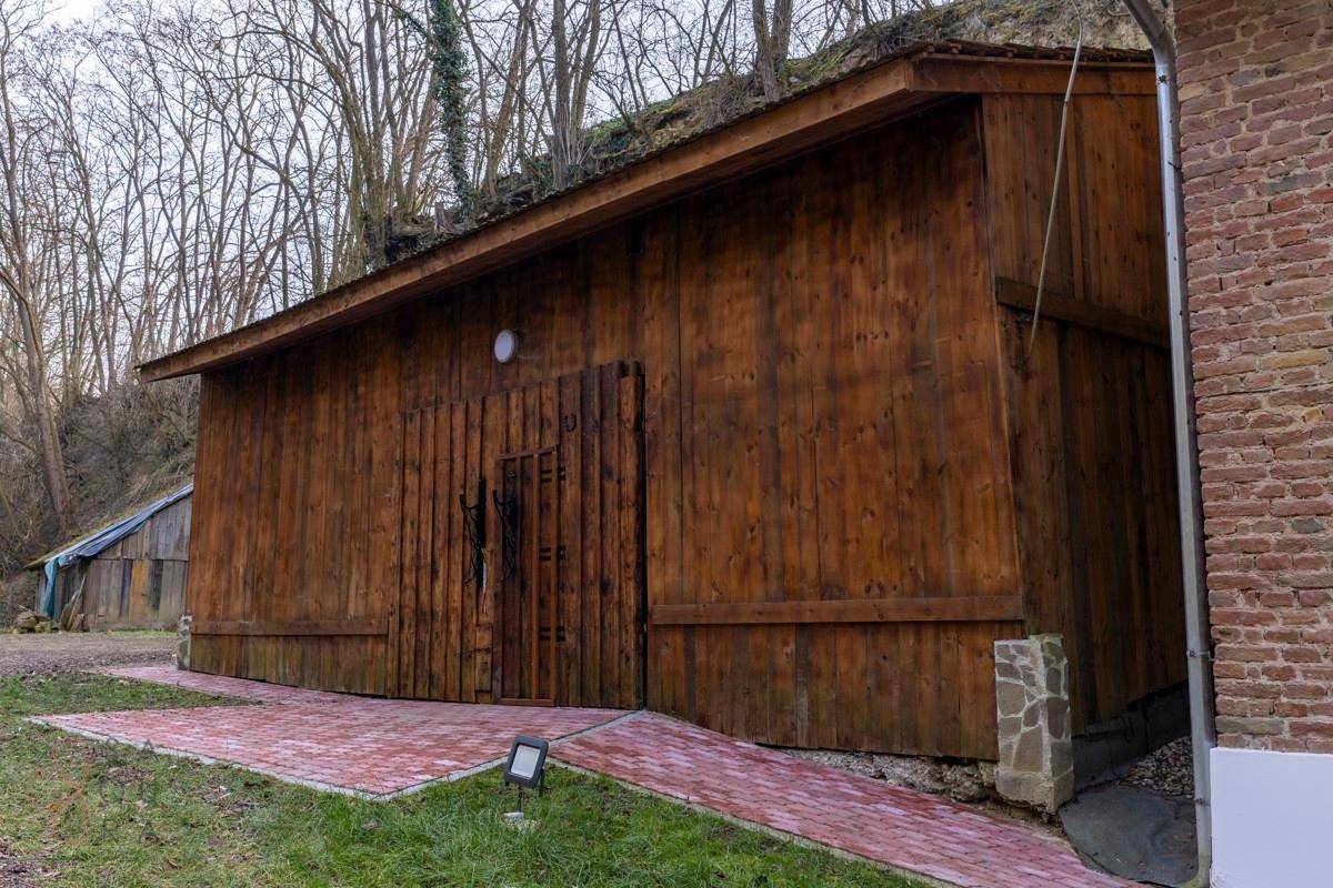 Rustikales Holzgebäude mit einfacher Architektur, eingebettet in eine natürliche, bewaldete Umgebung.