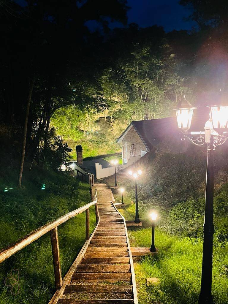 Romantisch beleuchteter Holzweg führt durch die Natur zu einem versteckten Haus im Wald.