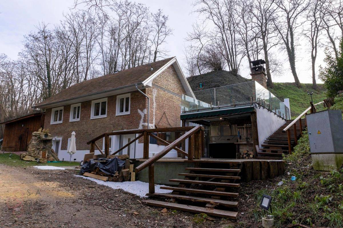 Seitenansicht des Hauses mit Backsteinfassade, Holzgeländer und einer Terrasse mit Glasbrüstung.