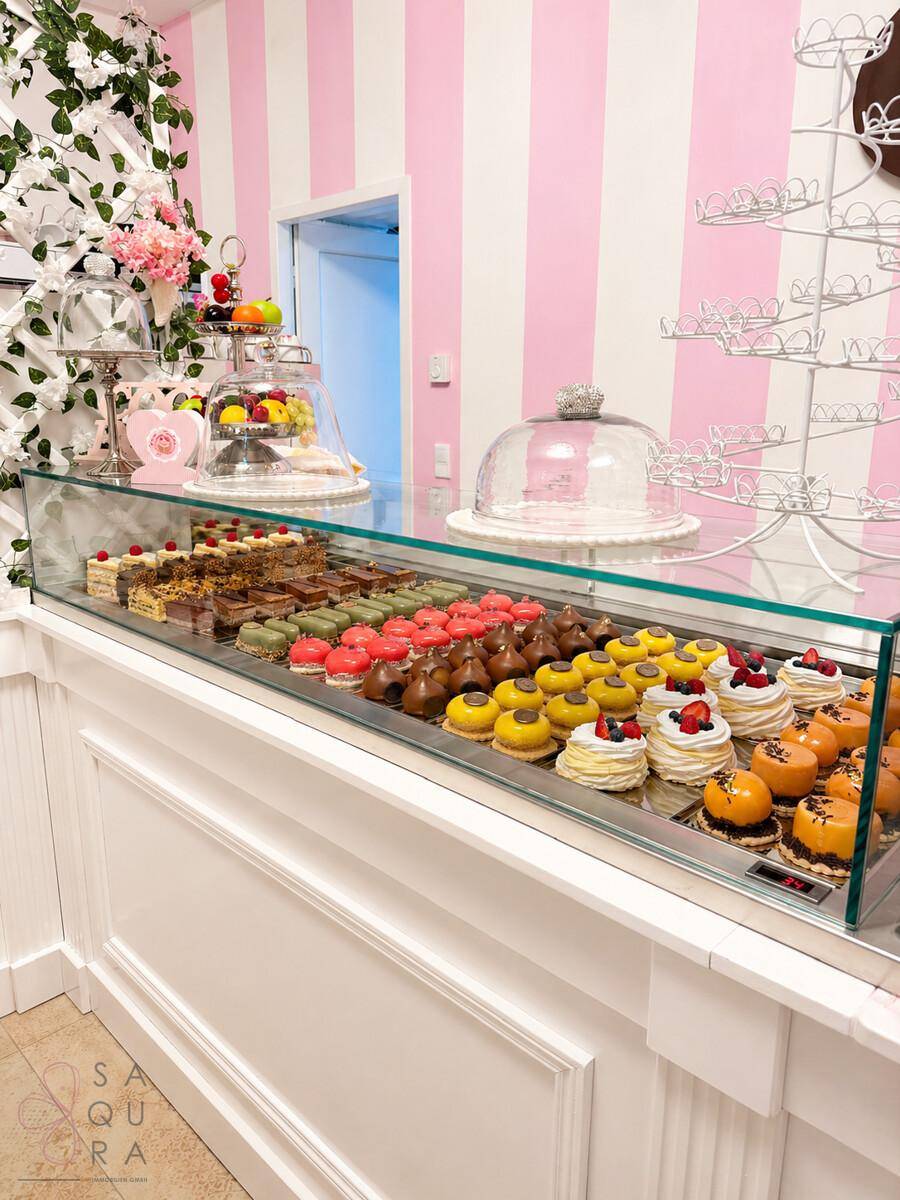 Thekenbereich mit einer großen Glasvitrine, gefüllt mit verschiedenen Gebäckstücken und Desserts.