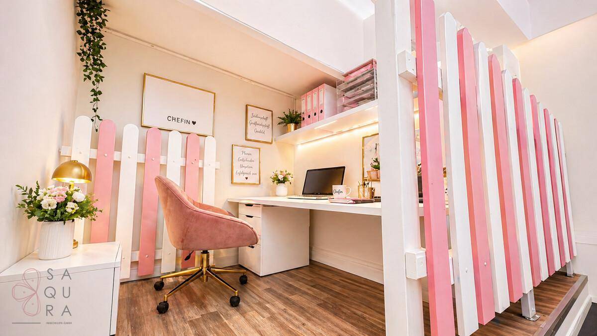 Gemütliches Büro auf einem Zwischengeschoss mit Schreibtisch, rosa Stuhl und dekorativen Elementen.