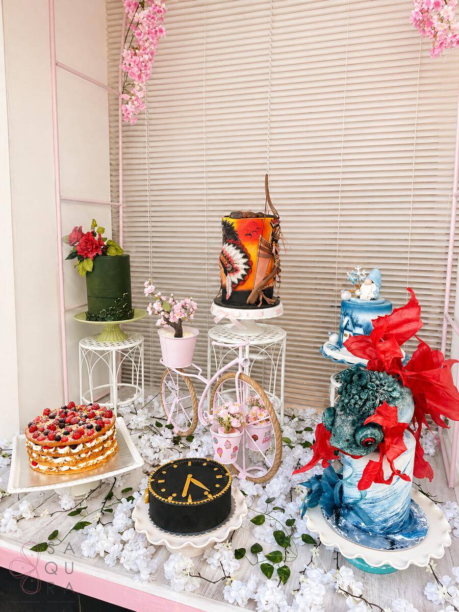Kreative Schaufensterdekoration mit verschiedenen kunstvollen Torten und Blumenarrangements.