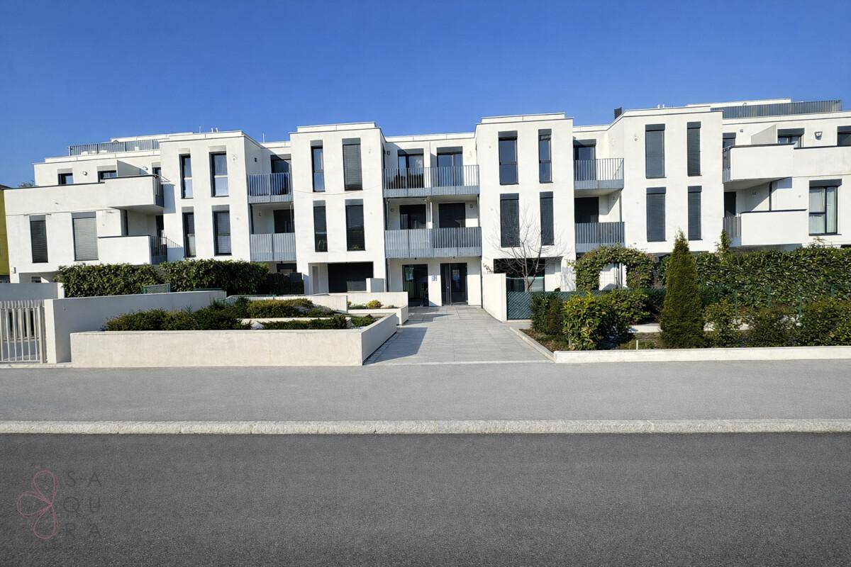 Moderne Wohnanlage mit weißer Fassade, Balkonen und gepflegten Grünflächen im Außenbereich.