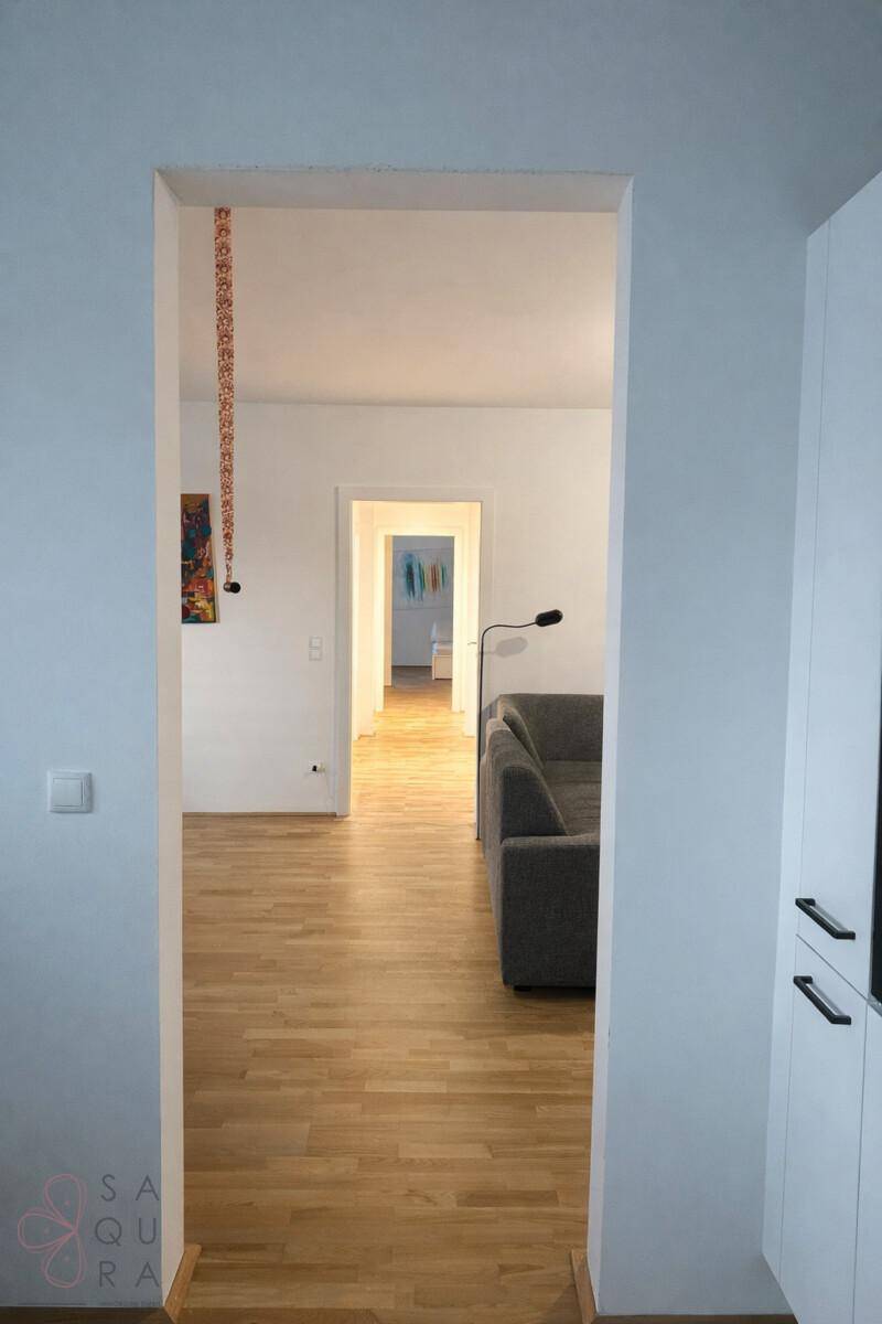 Heller Flur mit Holzboden, der zu den verschiedenen Räumen der Wohnung führt.