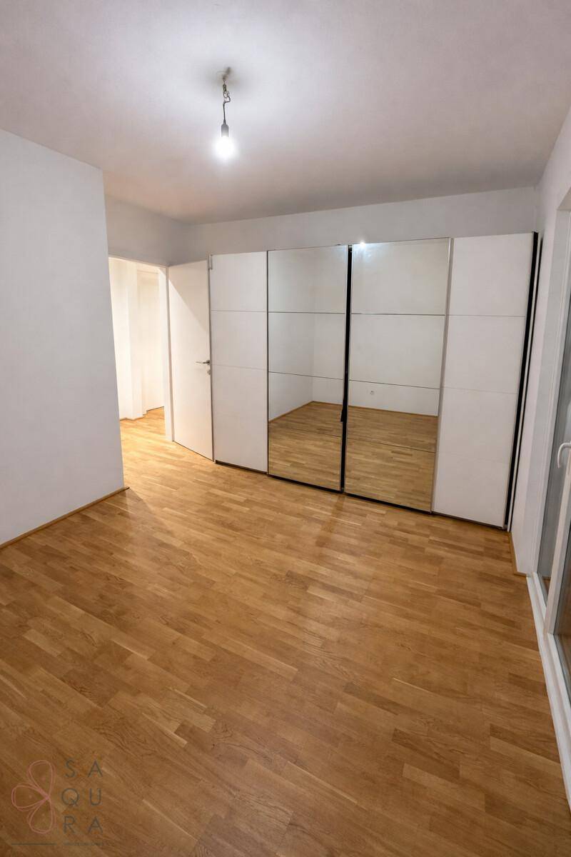 Schlafzimmer mit Holzboden und einem großen Spiegelschrank, der den Raum optisch vergrößert.