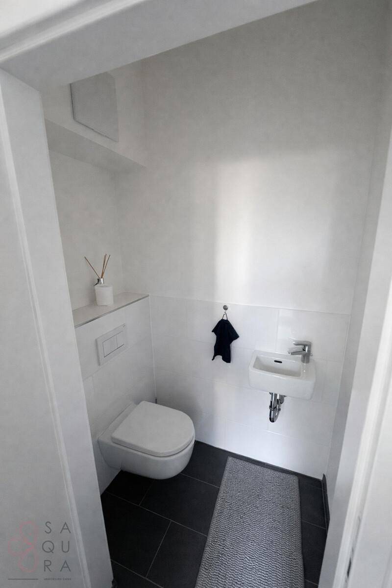Kleines, modernes Gäste-WC mit Wand-WC und Handwaschbecken, in schlichtem Design.