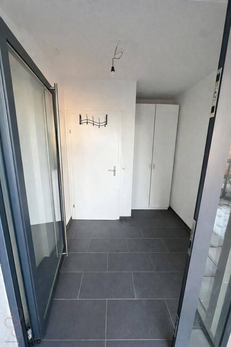 Eingangsbereich mit dunklen Fliesen, Garderobe und Zugang zu den Wohnräumen.