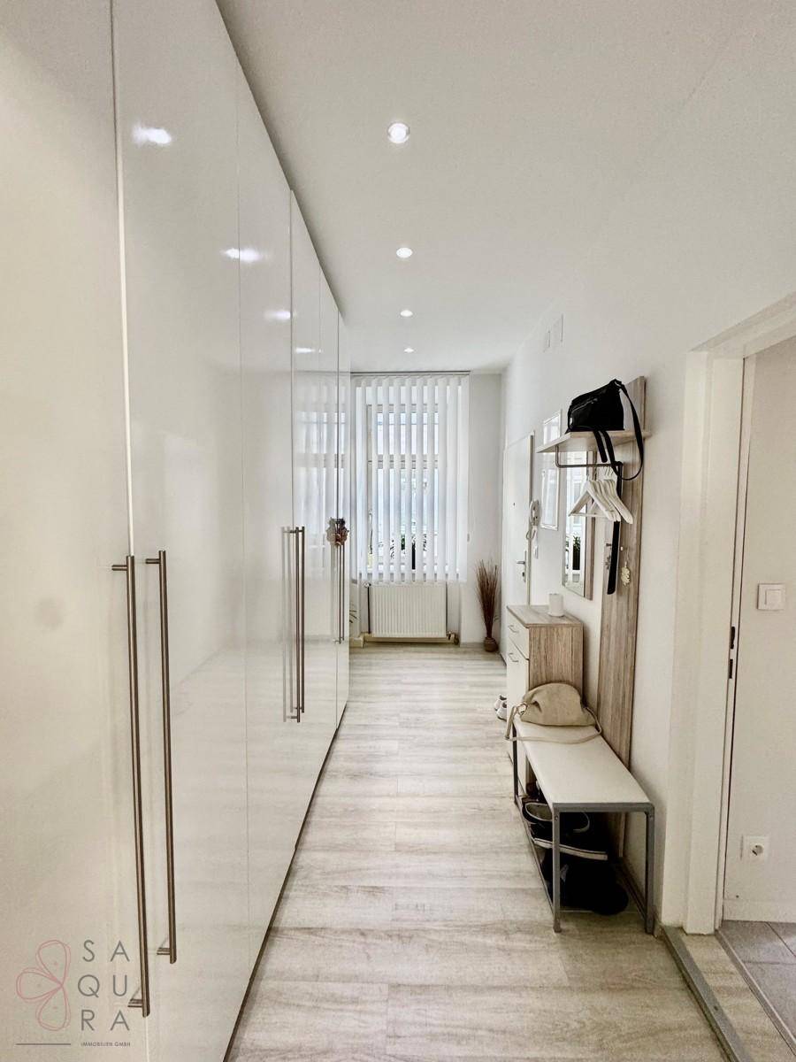 Langer, heller Flur mit glänzenden Einbauschränken und Garderobe, der viel Stauraum bietet.