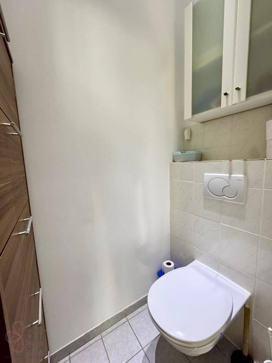 Separate Toilette mit wandhängendem WC und Fliesenboden, in schlichtem und funktionalem Design.