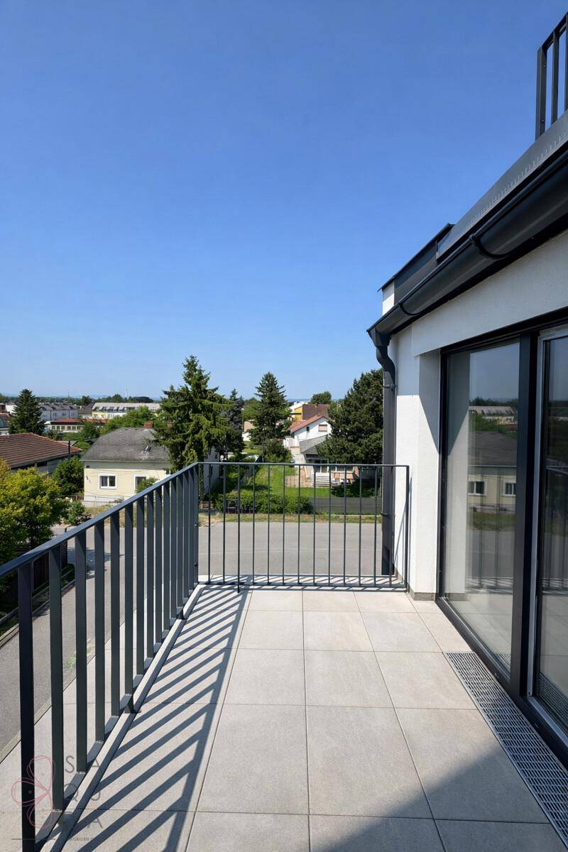 Heller Balkon mit Fliesenboden und Metallgeländer, bietet einen weiten Blick auf die Umgebung.