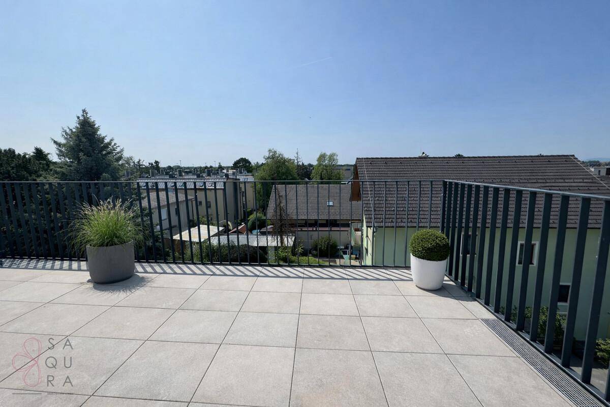 Geräumige Dachterrasse mit Fliesenboden, Metallgeländer und Topfpflanzen, mit Weitblick.