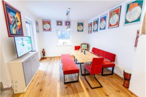 Heller Essbereich mit Holzboden, roter Sitzbank und Fernseher an der Wand.