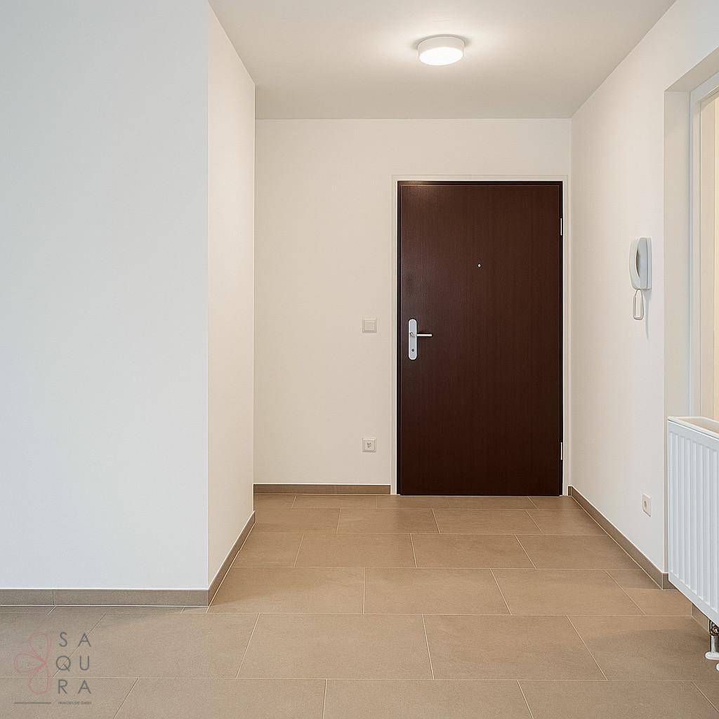 Eingangsbereich mit Fliesenboden, dunkler Tür und Gegensprechanlage, hell und einladend.