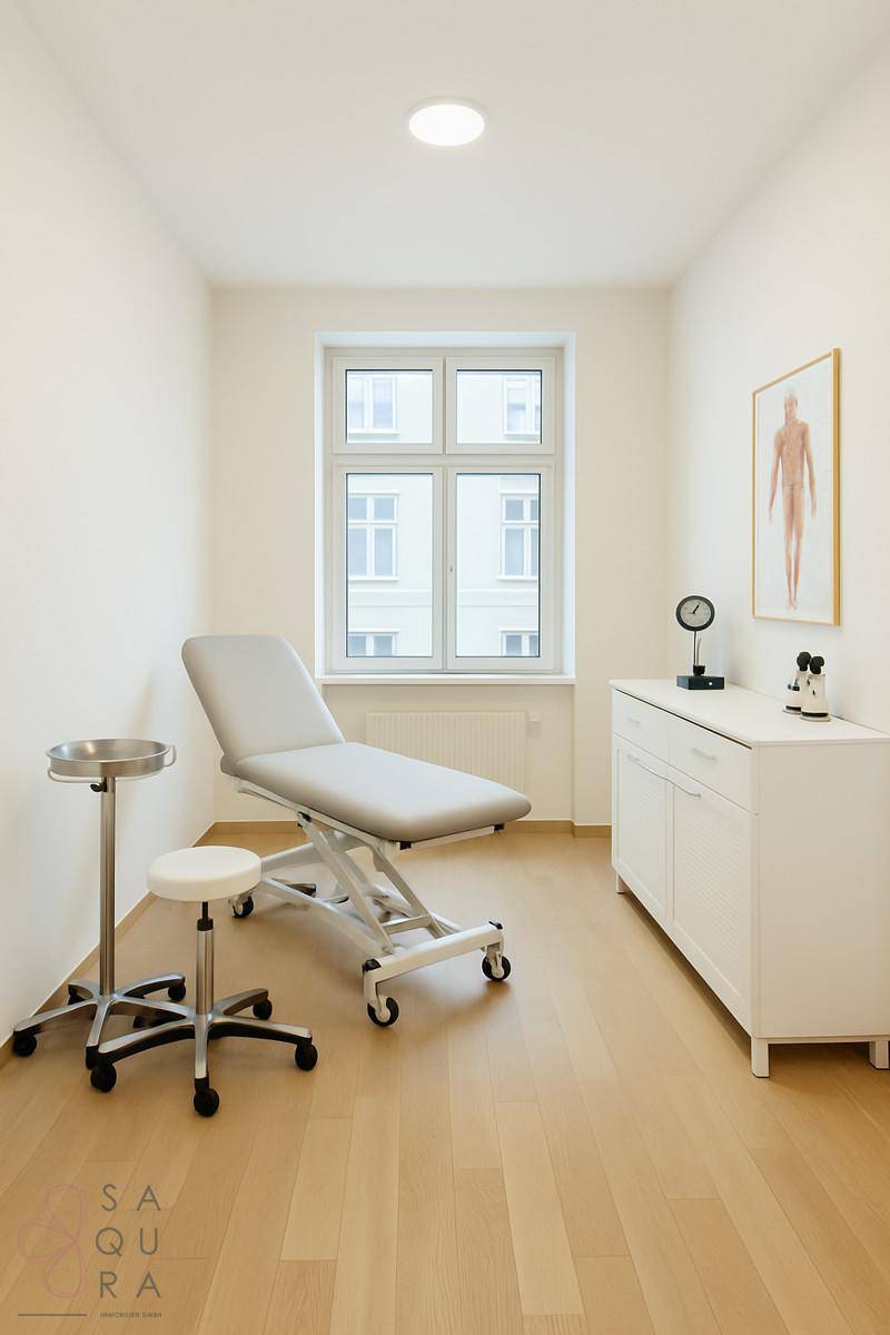 Helles Behandlungszimmer mit Holzboden, Fenster und medizinischer Ausstattung, ideal für eine Praxis.