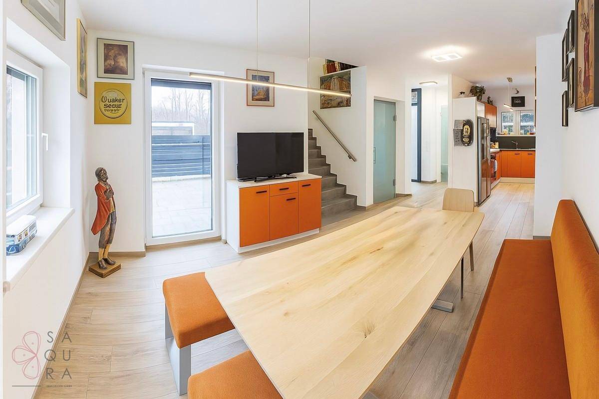 Heller Essbereich mit Holzboden, orangefarbenen Sitzbänken und Zugang zum Garten.