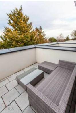 Dachterrasse mit modernen Outdoor-Möbeln und Blick auf Bäume.