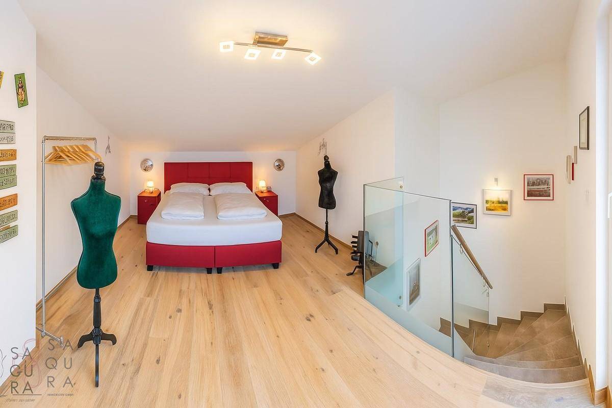 Geräumiges Schlafzimmer im Dachgeschoss mit Holzboden und offener Treppe.