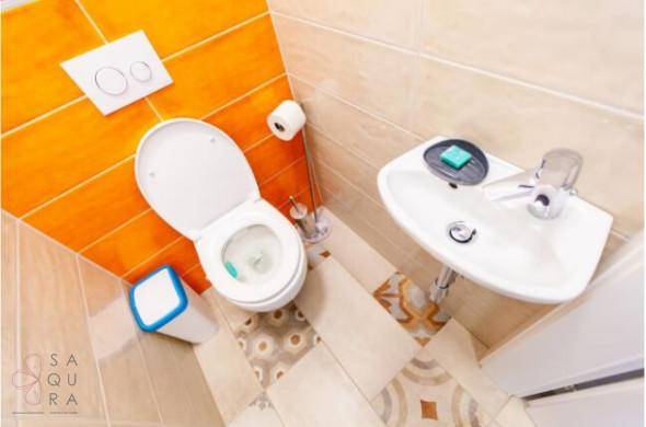 Kleines Gäste-WC mit orangefarbenen Fliesen und modernem Waschbecken.