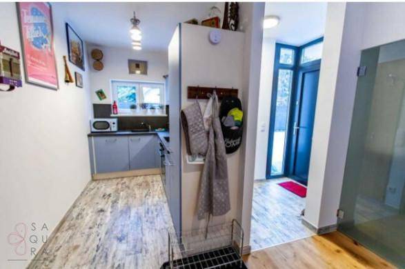 Eingangsbereich mit Garderobe und Blick auf eine kleine Küchenzeile.