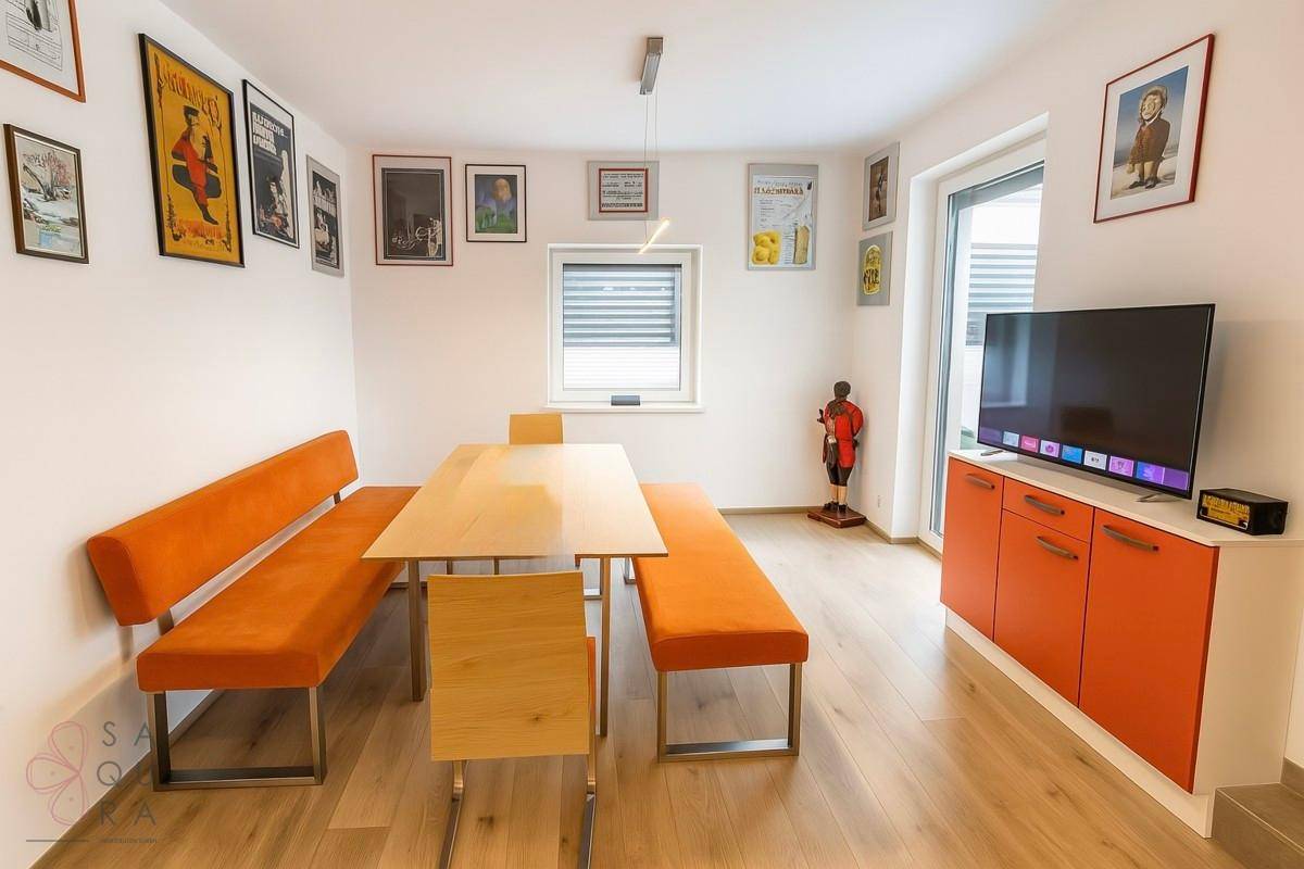 Essbereich mit Holzboden, orangefarbenen Sitzgelegenheiten und Fenster mit Jalousien.