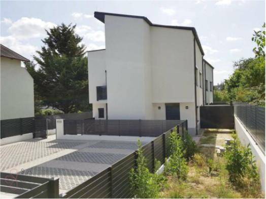 Rückansicht des Reihenhauses mit Parkplätzen und umzäuntem Bereich.