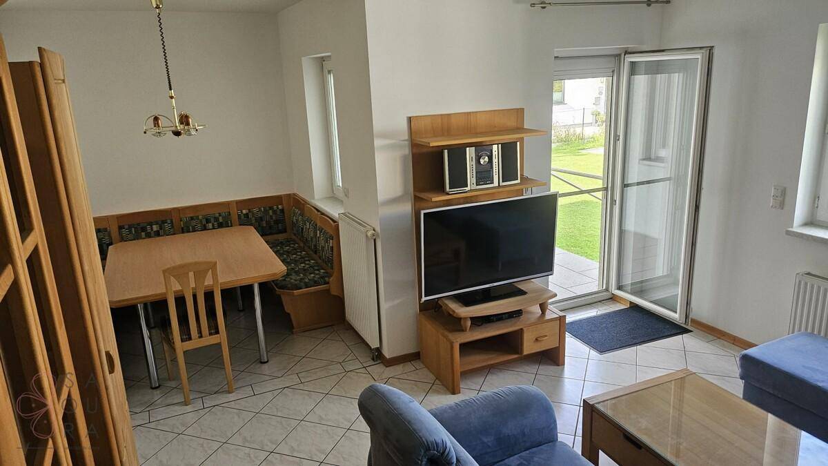 Gemütlicher Wohn-Essbereich mit Fernseher, Eckbank und direktem Gartenzugang.