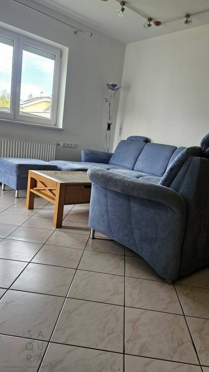 Geräumiges Wohnzimmer mit Fliesenboden und viel Tageslicht durch große Fenster.