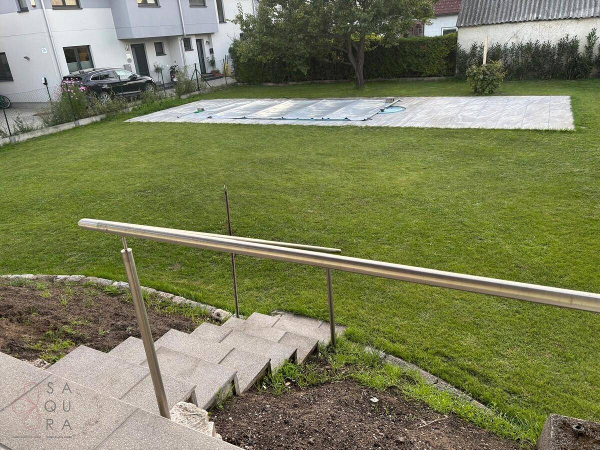 Blick auf die Treppe zum Haus und eine große Rasenfläche mit abgedecktem Pool.