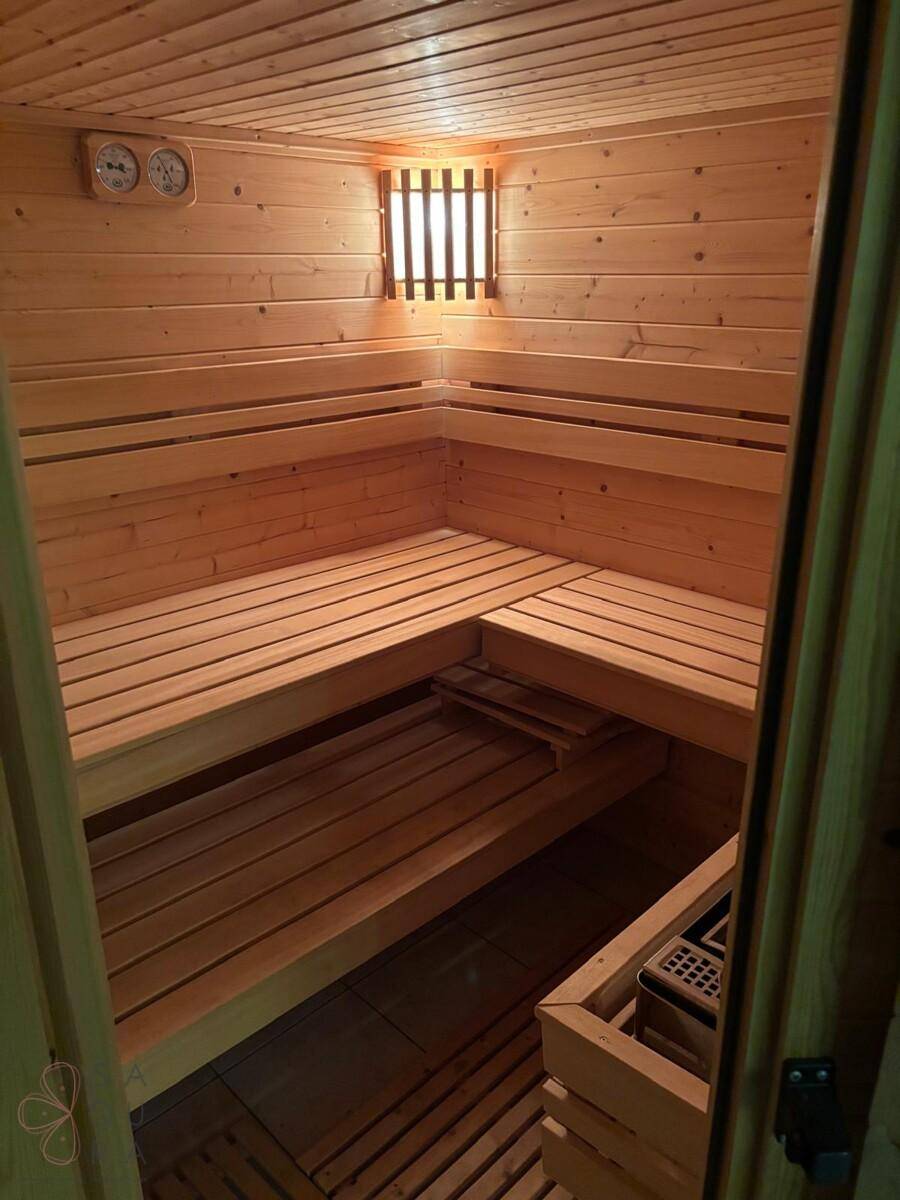 Gemütliche Holzsauna mit mehreren Bänken und traditionellem Saunaofen.