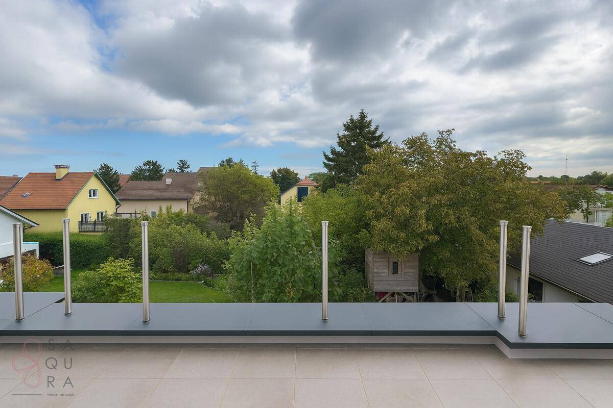 Eine geräumige Dachterrasse mit Fliesenboden und weitem Blick über die grüne Umgebung.