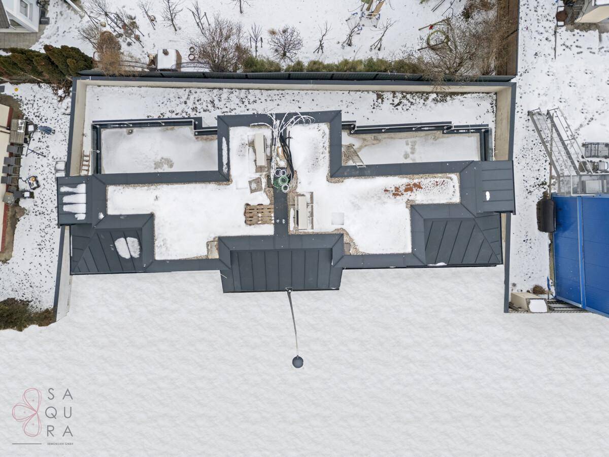 Eine Luftaufnahme des Neubaus im Winter, die die Dachstruktur und die verschneite Umgebung zeigt.