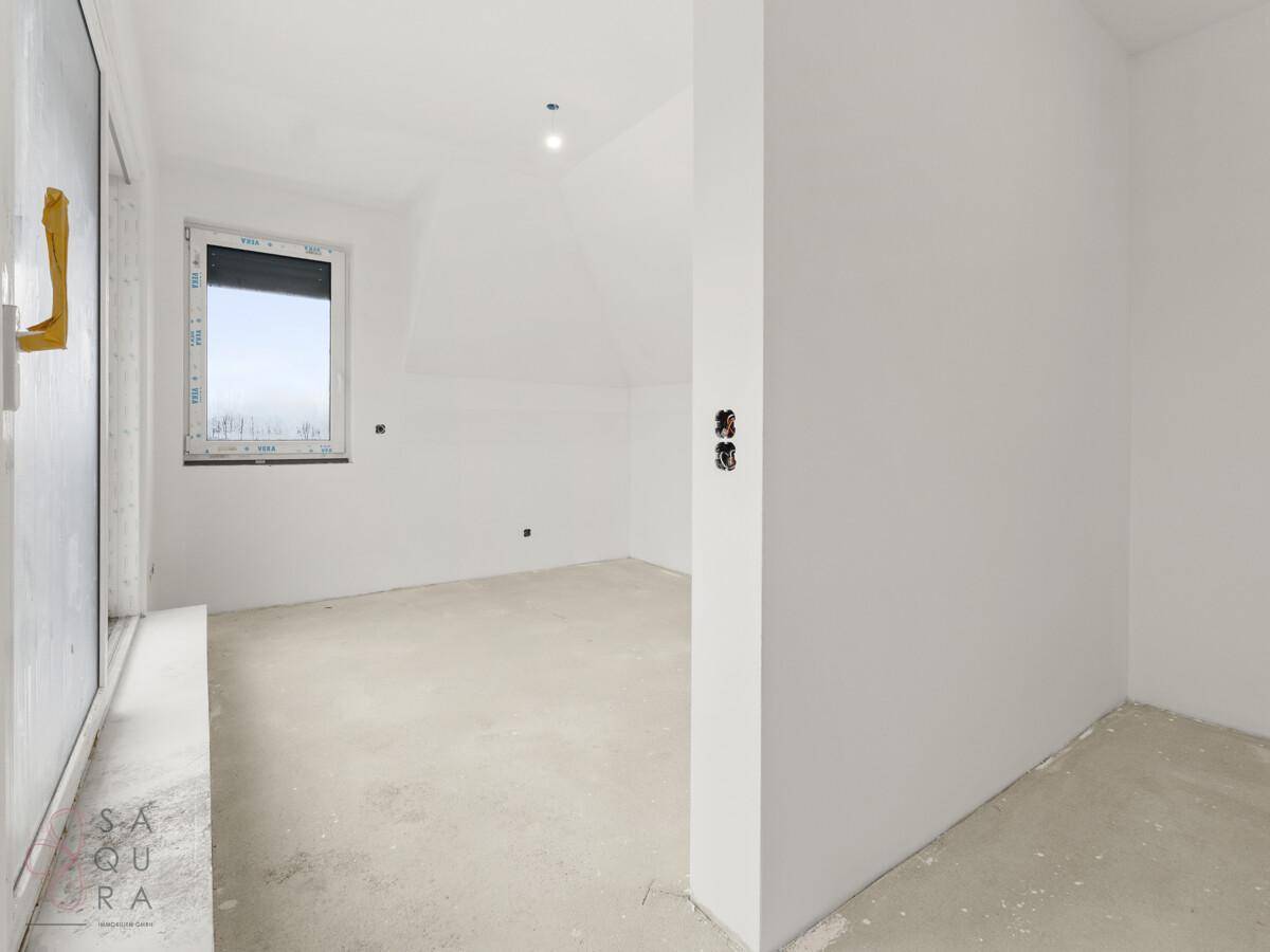 Unmöblierter Raum im Dachgeschoss mit Schrägdecke und Fenster, bereit für den Ausbau.