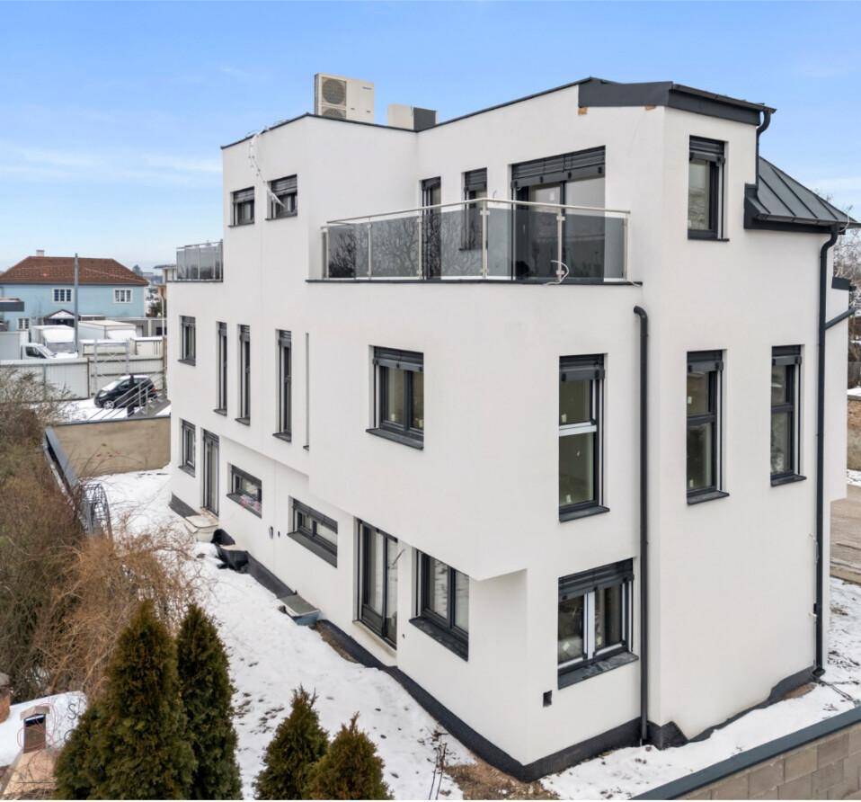 Eine weitere seitliche Ansicht des Neubaus im Winter mit Terrassen und Blick auf die Umgebung.
