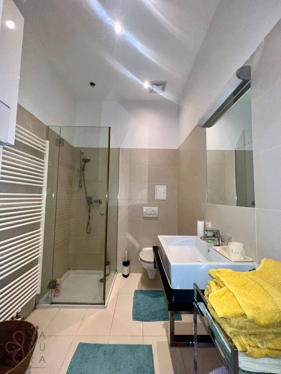 Modernes Badezimmer mit begehbarer Dusche, Einzelwaschbecken und beheiztem Handtuchhalter.