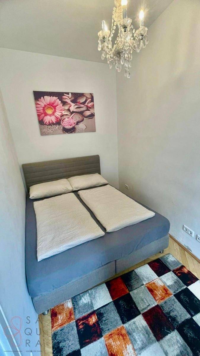 Gemütliches Schlafzimmer mit Doppelbett, Kronleuchter und farbenfrohem Teppichboden.