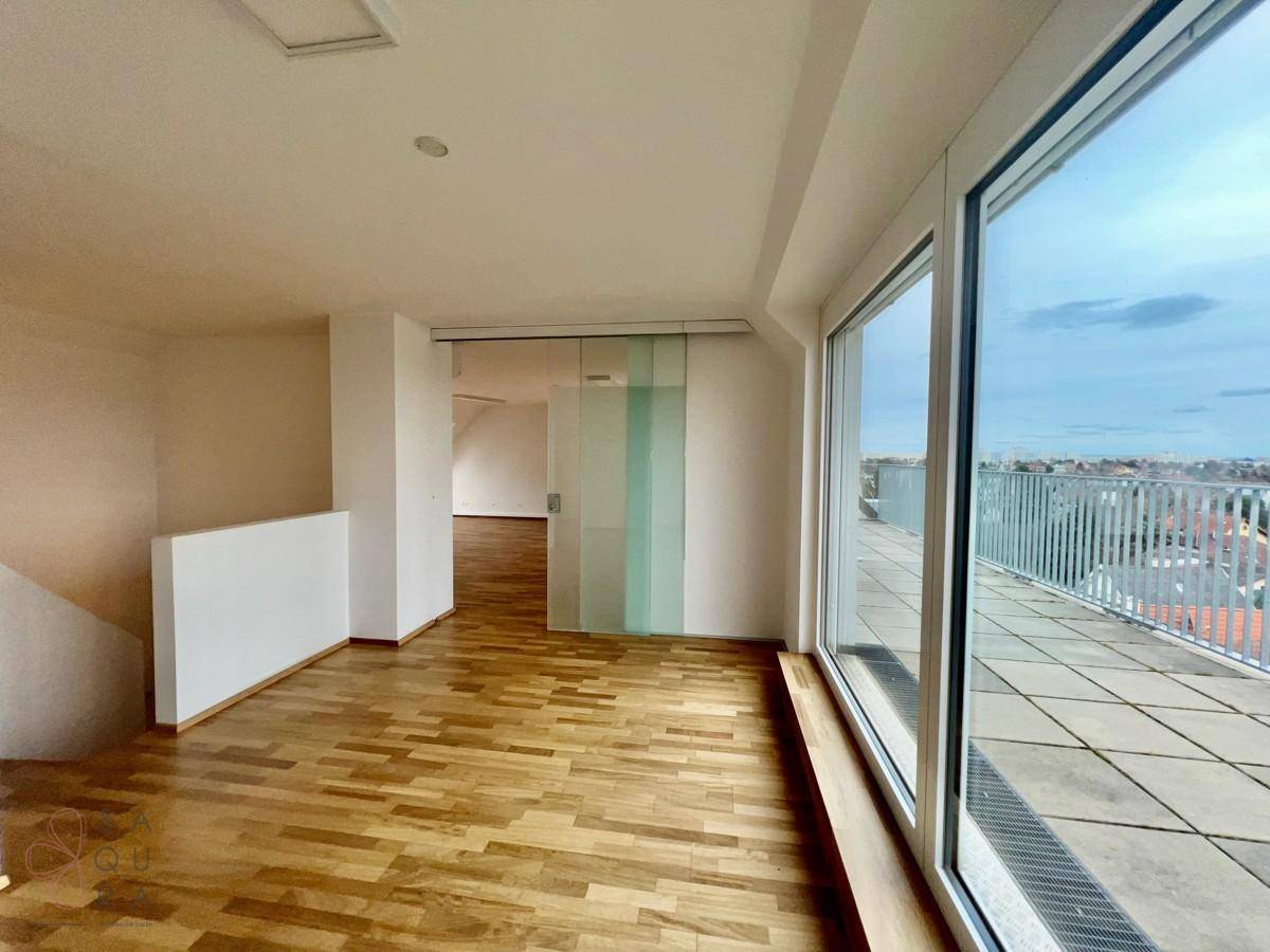 Heller Wohnbereich mit Holzboden und Zugang zu einer großzügigen Dachterrasse.