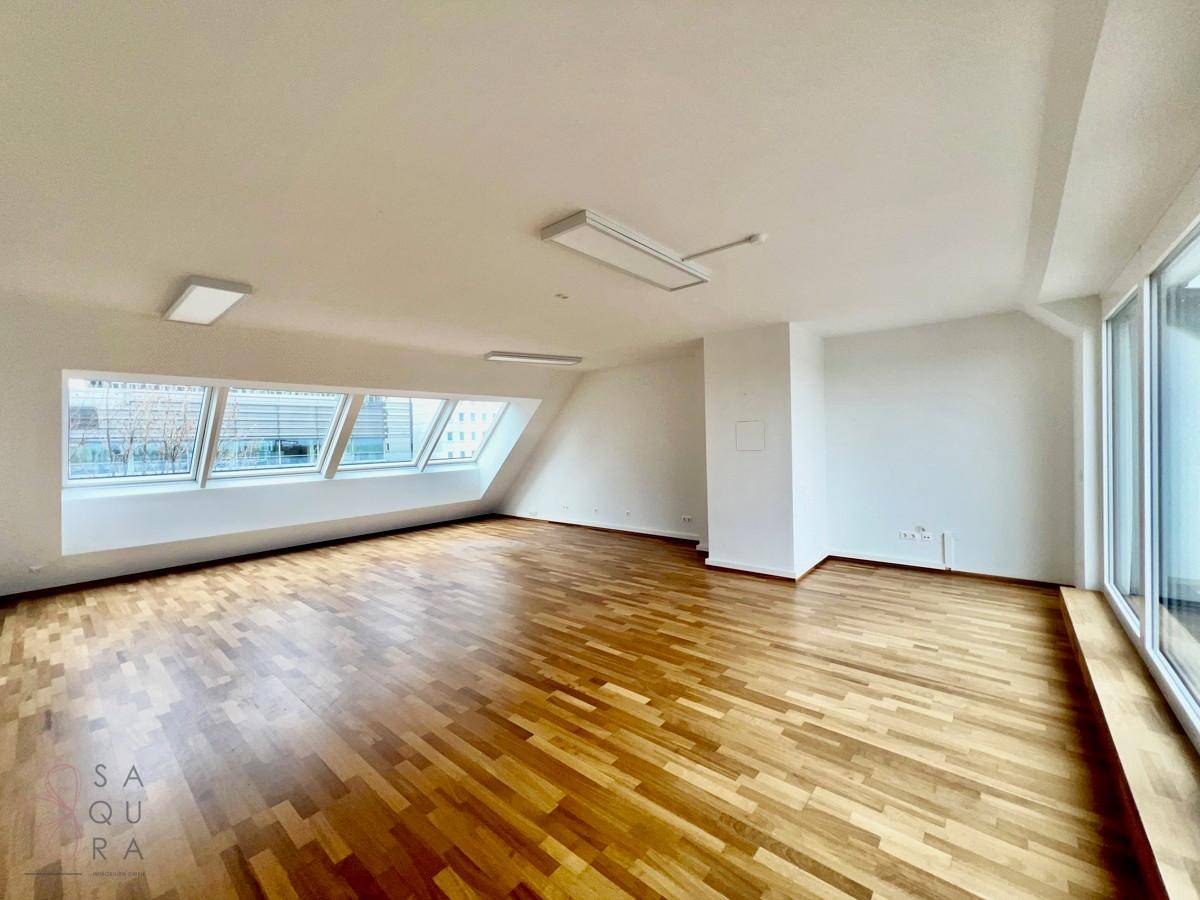 Geräumiges Zimmer mit Holzboden und schrägen Wänden, durch Dachfenster gut belichtet.