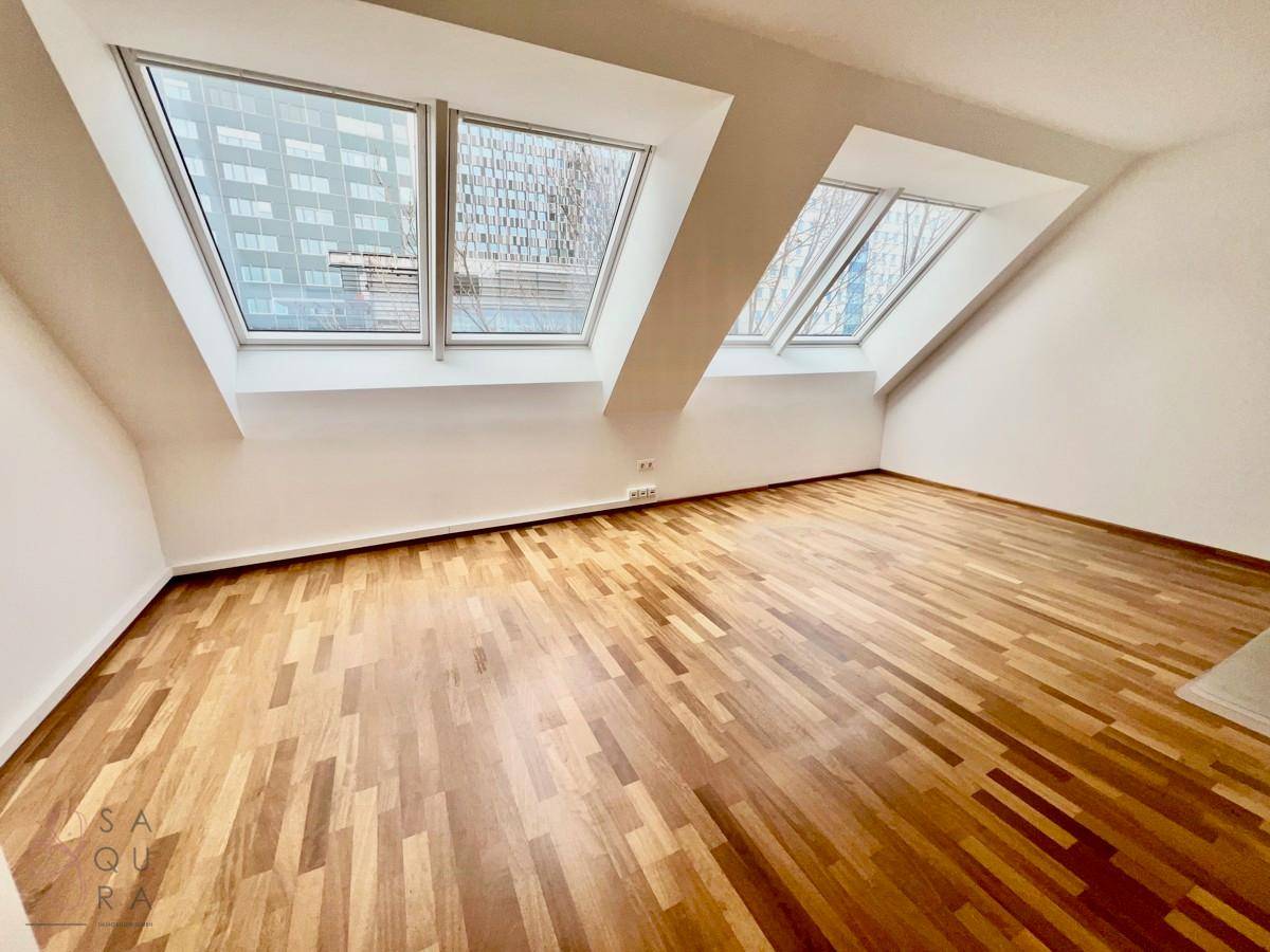 Helles Zimmer mit Holzboden und zwei Dachfenstern, bietet eine angenehme Wohnatmosphäre.