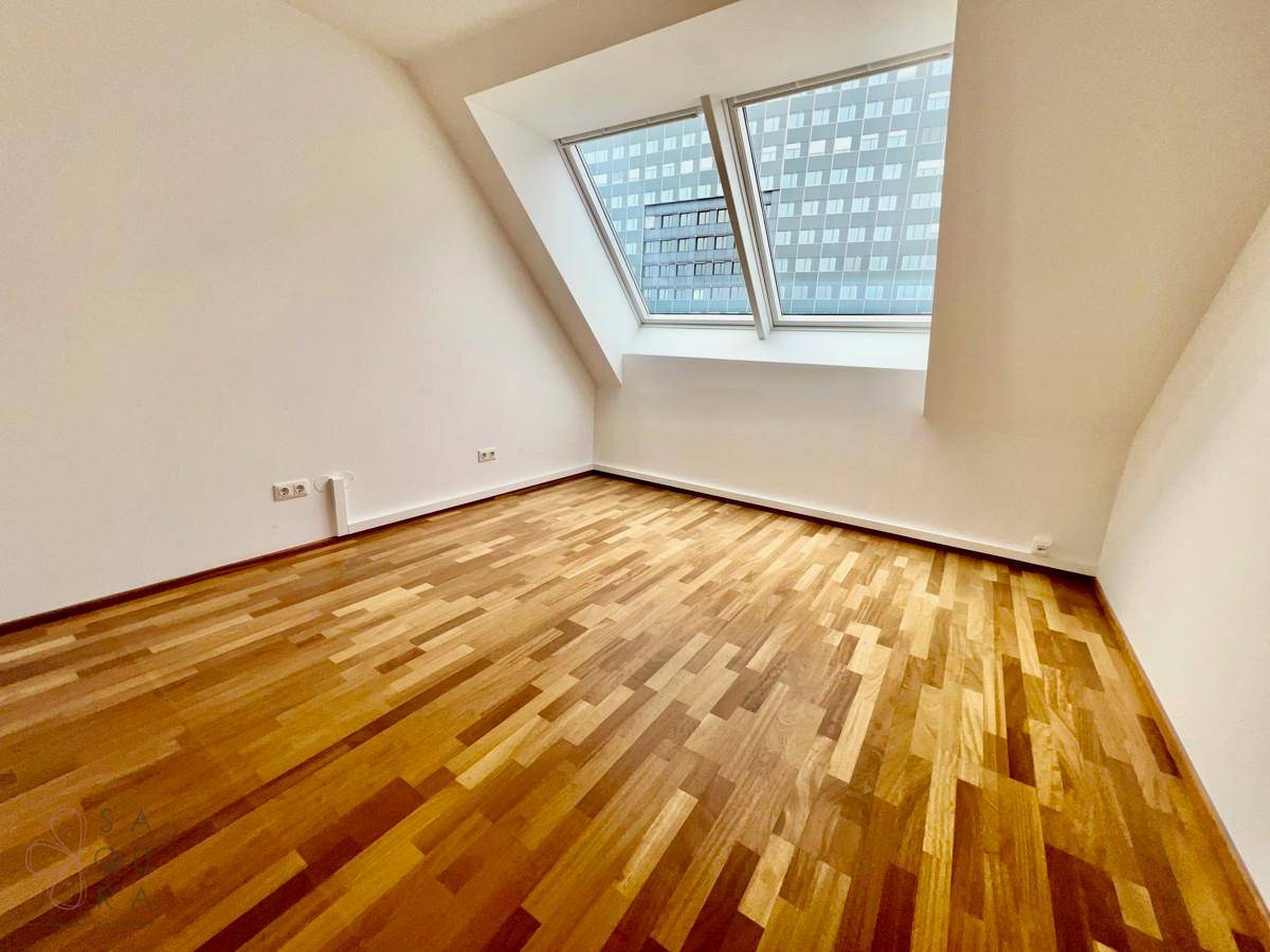 Ruhiges Zimmer mit Holzboden und Dachfenster, ideal als Schlaf- oder Arbeitszimmer.