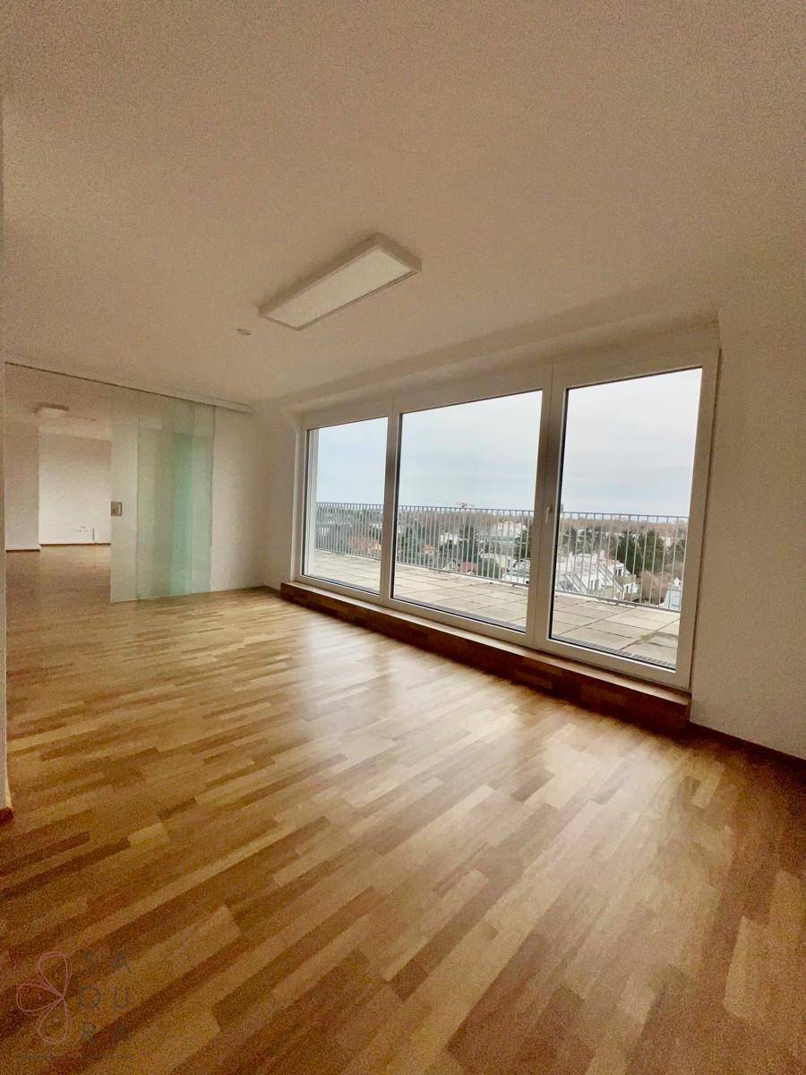 Lichtdurchfluteter Raum mit Holzboden und breiter Fensterfront, bietet weite Ausblicke.