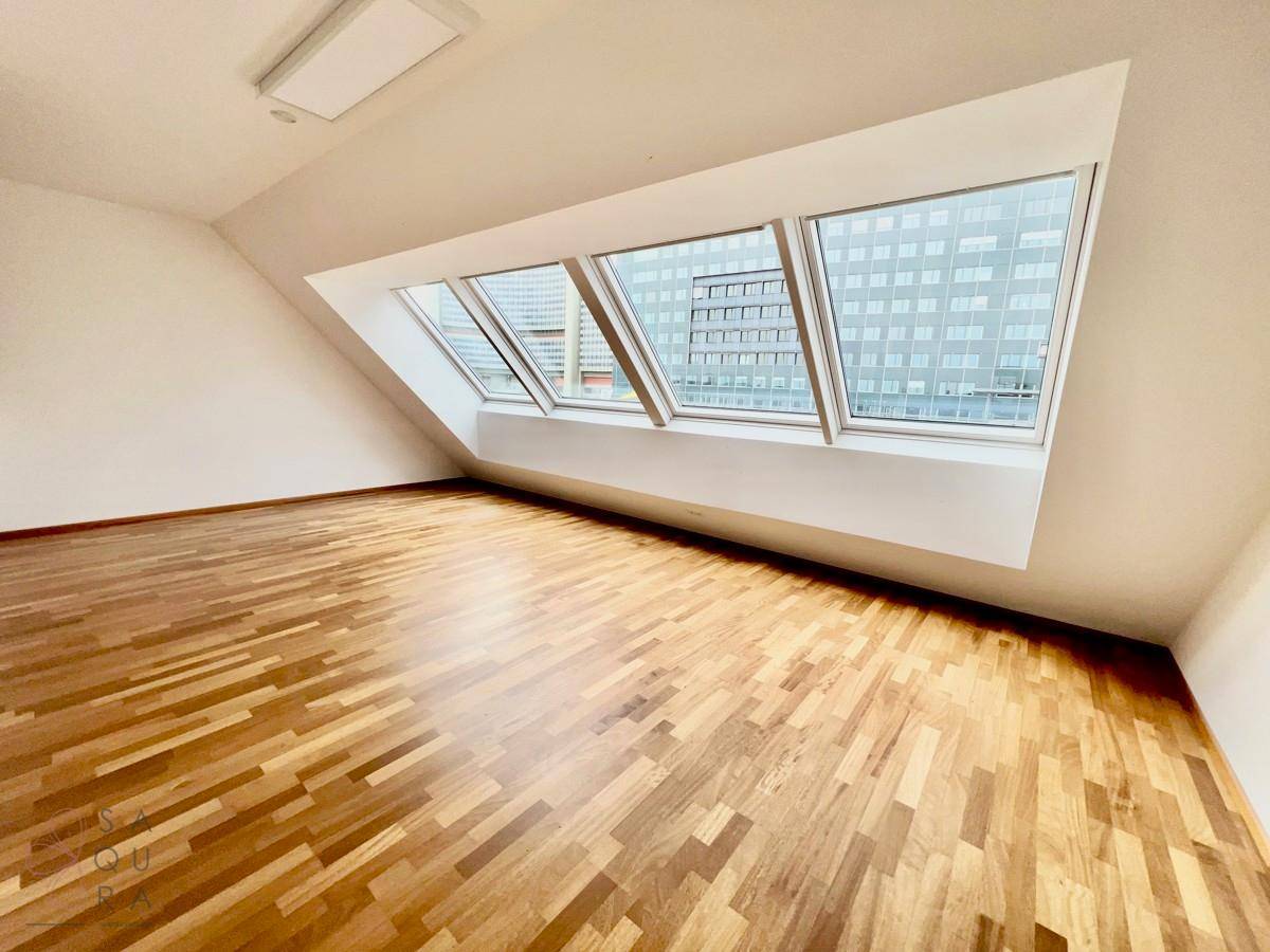Gemütliches Zimmer mit Holzboden und schrägen Wänden, durch Dachfenster gut belichtet.