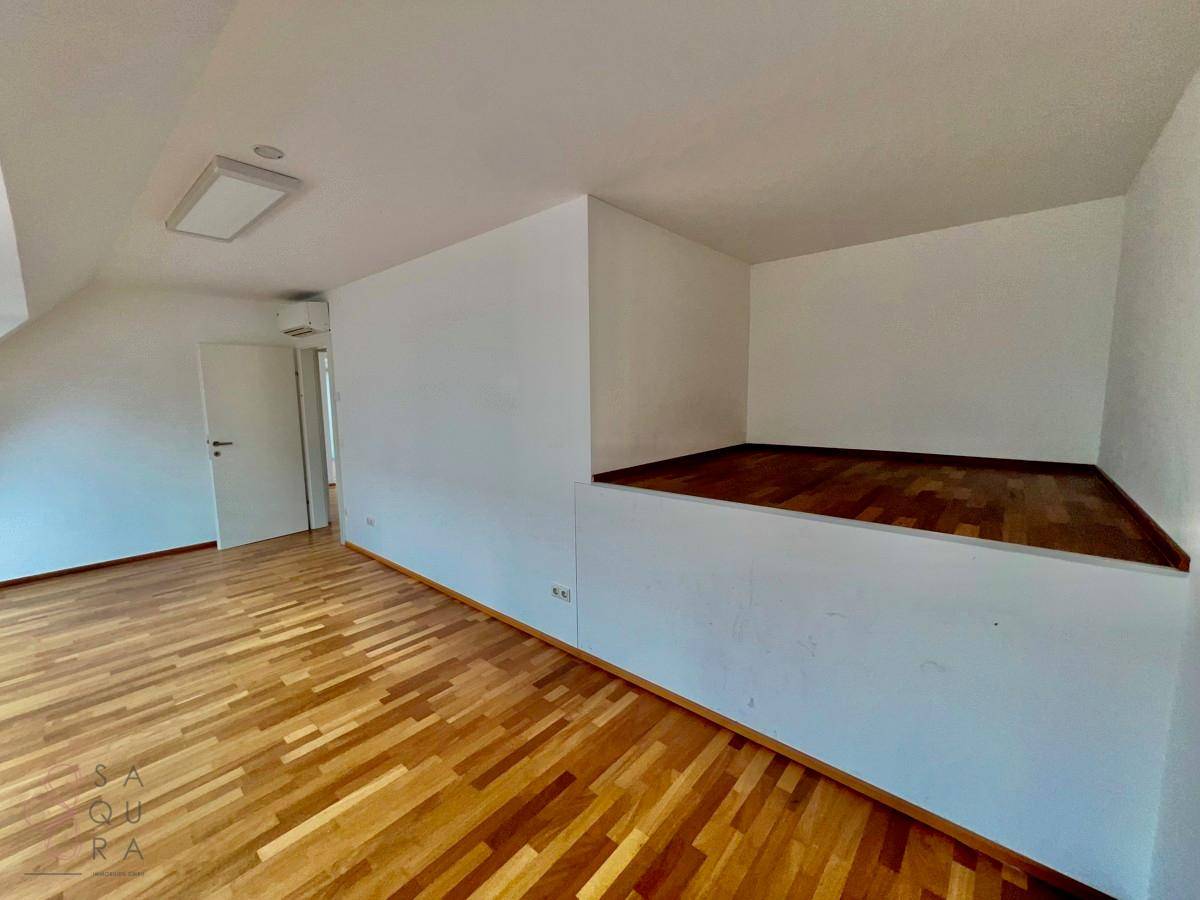 Innenraum mit Holzboden und einer erhöhten Plattform, bietet flexible Nutzungsmöglichkeiten.