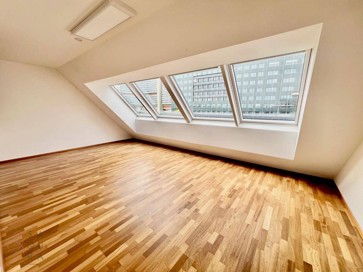 Helles Zimmer mit Holzboden und schrägen Wänden, durch Dachfenster gut belichtet.
