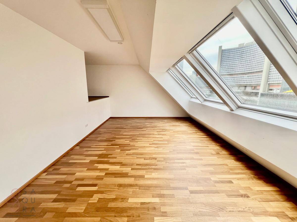 Lichtdurchflutetes Zimmer mit Holzboden und Dachfenstern, bietet einen weiten Ausblick.