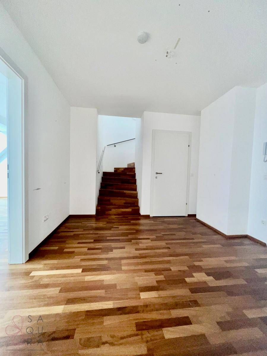 Heller Eingangsbereich mit Holzboden und Treppenaufgang, führt zu den oberen Etagen.