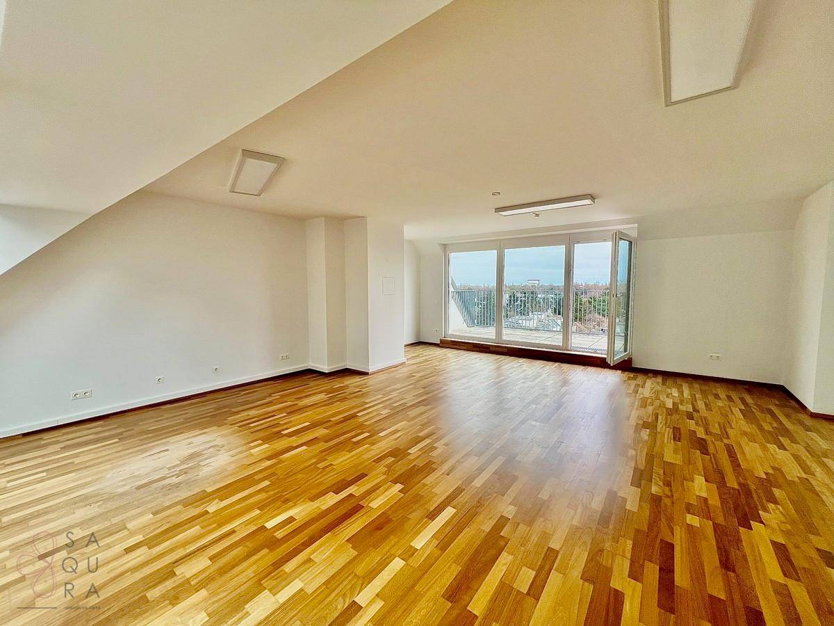 Geräumiger Wohnbereich mit Holzboden und großer Fensterfront, bietet weite Ausblicke.